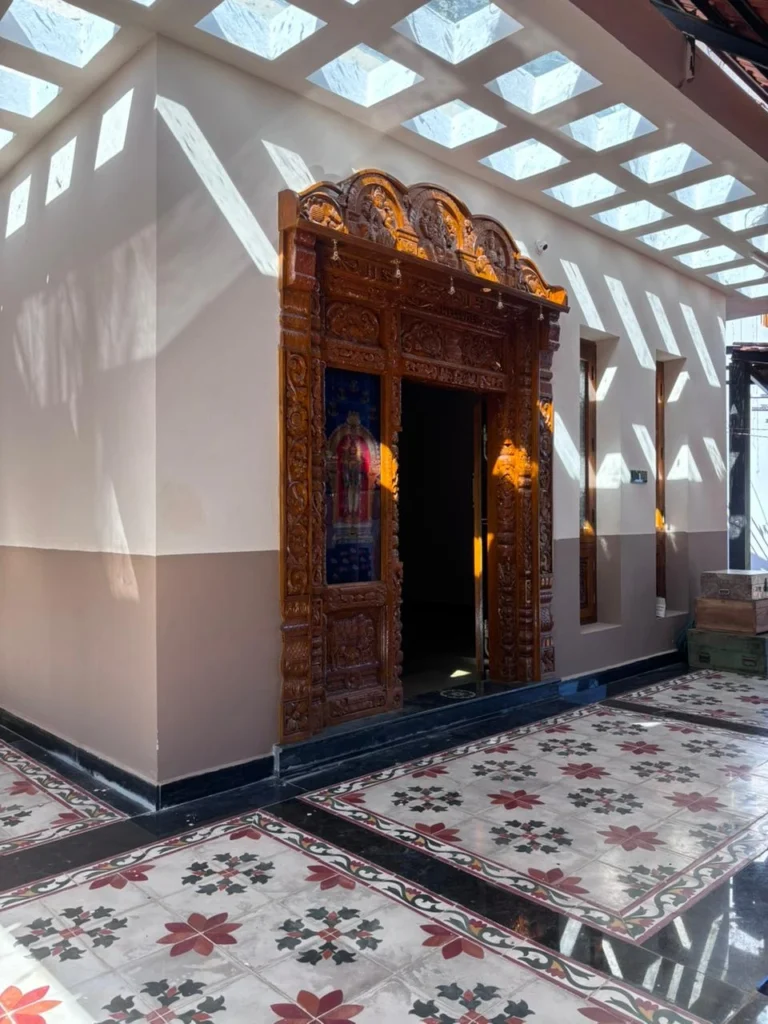 Entry — carved teak door and patterned floor beneath the skylight grid